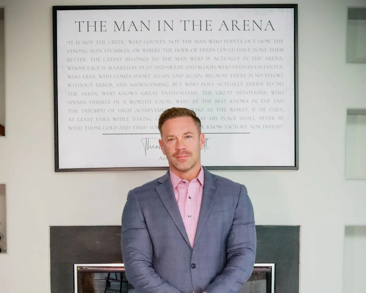 Adam Lamb beside a framed print of The Man in the Arena